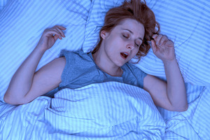 Woman lying on her back in bed snoring